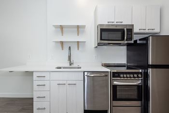 A modern kitchen with stainless steel appliances and white cabinetry. at RiDE at RiNo Apartments, Denver, CO, 80216